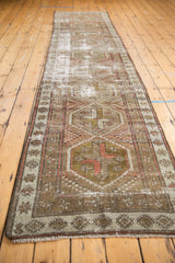 Distressed Caucasian runner rug with full length geometric medallions and worn texture in red, green, ivory.