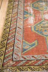Detail of Northwest Persian runner's olive green border, striped bands, and worn brick red pile.