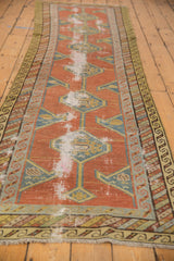 Antique Northwest Persian runner with geometric brick red field, teal medallions, and wear to foundation.