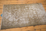 Distressed Malayer rug corner revealing visible foundation wear and muted beige, gold, sage tones.