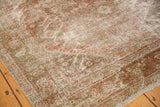 Distressed vintage Mahal carpet close-up, floral pattern with dusty blush, coffee brown, and even wear.