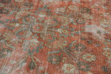 Distressed vintage Mahal carpet close-up: worn soft red pile, faded blue-green floral vinery.