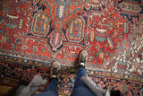 Detailed view of vintage Heriz carpet's brick red field with serrated leaves and floral motifs.
