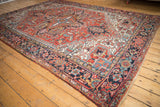 Vintage Heriz rug corner, displaying intricate navy blue borders and a brick red geometric field.