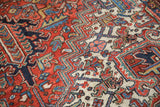 Vintage Heriz rug with geometric, serrated leaf pattern in brick red, ivory, and navy blue.