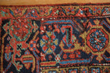 Vintage Heriz carpet detail: low pile, serrated leaf and floral motifs in red, navy, gold.