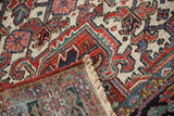 Hand-knotted Heriz rug pile: low, brick red, ivory, blue floral patterns, woven back, and fringe.
