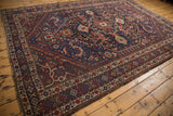 Vintage Shiraz carpet corner: intricate floral border and tribal motifs in deep blue and madder red.