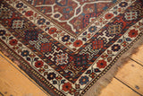 Vintage Shiraz carpet corner, intricate madder red, blue geometric borders, secure fringe, even wear.