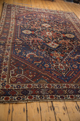 Madder red and navy blue patterns on hand-knotted vintage Shiraz rug, showing mostly even wear.