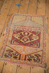 Distressed vintage Oushak rug section showing geometric diamond motif and brick red, dusty gold hues.