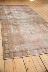 Distressed dusty blush and antique ivory tones on the Oushak runner's secured end.