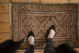 Staggered geometric medallion on vintage Belouch mat, dusty blush, chocolate, and ivory tones.