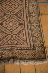 Vintage Belouch rug corner detail: geometric diamond patterns in chocolate, dusty blush, beige, with fringe.
