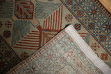 Folded corner of distressed vintage Afghani rug showing woven foundation and geometric patterns.