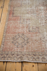 Vintage distressed Oushak rug runner with worn low pile, border detail, and blush, beige, and time-softened tones.