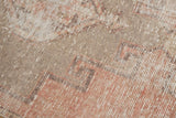 Distressed texture and geometric pattern of vintage Oushak rug in dusty blush and beige.