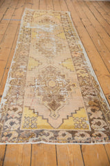 Geometric stepped medallion and distressed pile on a soft saffron and beige Oushak runner.