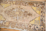 Distressed vintage Oushak rug detail showing saffron field, stepped motifs, and wear to foundation.