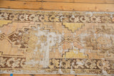 Distressed Oushak runner with exposed foundation, visible knot heads, and stepped geometric patterns in saffron beige.
