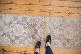 Vintage distressed Oushak runner with faded violet, denim blue, ivory floral patterns, even wear.