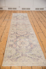 Distressed Oushak rug close-up showing faded violet, ivory floral motifs, and even pile wear.