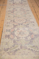 Textured distressed Oushak runner pile with even wear and faded violet, green, and peach hues.