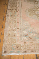 Angled close-up of the vintage Oushak runner's fringed end and geometric side border in pale blush.