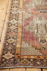 Close-up of distressed vintage Oushak rug border, geometric patchwork, saffron, and aubergine.
