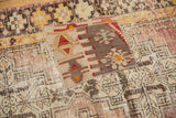 Hand-stitched geometric kilim patch in red, brown, and beige on a distressed Oushak rug.