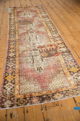 Close-up of vintage distressed Oushak runner showing geometric patchwork, worn pile, and aubergine, saffron, ivory tones.