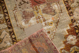 Pale neutral patchwork on distressed vintage Oushak rug, folded reverse showing reddish hues.