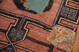 Distressed vintage Kars rug detail: blush geometric pattern and colorful textile reinforcement patches.