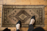 Low pile texture of a distressed vintage Oushak rug mat in beige and brown.
