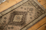 Distressed chocolate brown stepped medallion with germinating plant motif on vintage Oushak rug.