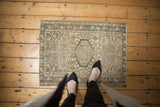 Distressed vintage Karaja rug corner with geometric floral motifs in sand and muted green.