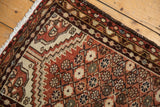 Distressed Hamadan rug close-up showing floral lattice motif in rust and ivory tones.
