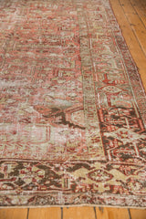 Distressed Heriz carpet fringed corner with pale raspberry and sage geometric patterns.