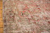 Geometric floral and leaf patterns with time-softened tones on a vintage Heriz carpet.