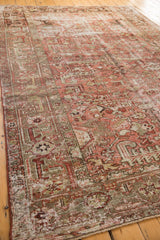Distressed vintage Heriz carpet corner, geometric floral pattern, worn pile, and secured side.