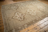 Distressed Oushak rug corner showing geometric border and tonal medallion with low pile.