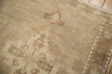 Low pile, distressed texture of a vintage Oushak carpet, showing faded patterns.
