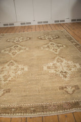 Distressed Oushak carpet's low pile and visible knot heads in neutral tones.