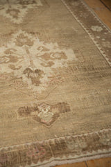 Low pile texture of distressed vintage Oushak carpet, with faded beige and sand-toned patterns.