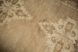 Distressed vintage Oushak carpet texture, revealing low pile and subtle beige, sand patterns.
