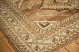 Distressed Oushak rug corner showcasing geometric border, wave motif, and low pile.