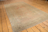 Distressed vintage Oushak carpet with soft blush, ivory, and ocean green geometric patterns.
