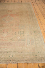 Faded geometric patterns in blush, ocean green, and ivory on a distressed Oushak rug with low pile.