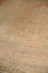 Distressed Oushak carpet's low pile texture with faded rose and subtle geometric patterns.
