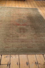 Distressed Oushak carpet with low pile, abrashes, and muted rose and green tones.